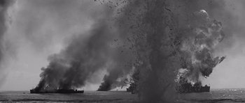 Movie still from “In Harm's Way” (1965), directed by Otto Preminger – A black - and - white photo of a ship on fire; Extreme Wide shot, High angle