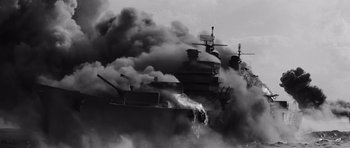 Movie still from “In Harm's Way” (1965), directed by Otto Preminger – Smoke billows out of a burning ship in a black and white photo; Extreme Wide shot, Low angle