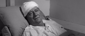 Movie still from “In Harm's Way” (1965), directed by Otto Preminger – An older man in a hospital bed with a bandage on his head; Close Up shot, High angle