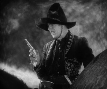 Movie still from “In Old Arizona” (1928), directed by Raoul Walsh – An old photo of a man holding a cell phone; Medium shot, Low angle