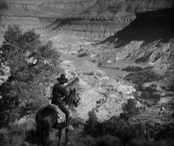 Movie still from “In Old Arizona” (1928), directed by Raoul Walsh – A man riding a horse in the middle of a valley; Extreme Wide shot, High angle