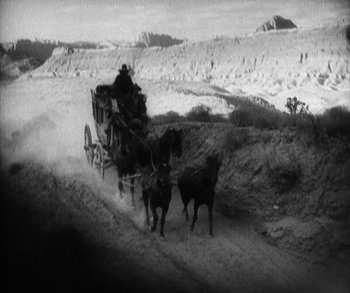 Movie still from “In Old Arizona” (1928), directed by Raoul Walsh – Two horses pulling a carriage down a dirt road; Extreme Wide shot, High angle