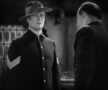 Movie still from “In Old Arizona” (1928), directed by Raoul Walsh – A man in a uniform talking to another man in a hat; Medium shot, Over the shoulder angle