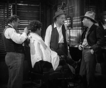 Movie still from “In Old Arizona” (1928), directed by Raoul Walsh – A group of men standing next to each other in a room; Medium shot, Over the shoulder angle