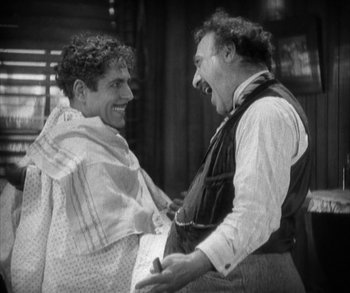 Movie still from “In Old Arizona” (1928), directed by Raoul Walsh – Two men are laughing together in a room; Medium shot, High angle