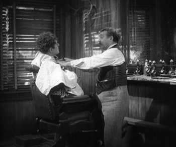 Movie still from “In Old Arizona” (1928), directed by Raoul Walsh – An old photo of a man cutting a woman's hair; Medium shot, Over the shoulder angle