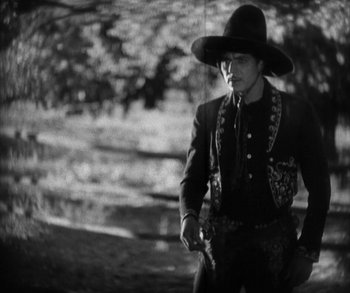 Movie still from “In Old Arizona” (1928), directed by Raoul Walsh – A man wearing a cowboy hat and holding a gun; Medium shot, Low angle