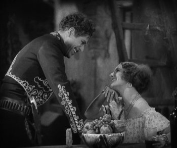 Movie still from “In Old Arizona” (1928), directed by Raoul Walsh – A man and a woman sitting in front of a bowl of fruit; Medium shot, High angle