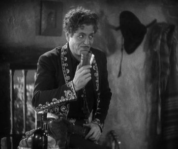 Movie still from “In Old Arizona” (1928), directed by Raoul Walsh – A black and white photo of a man holding a knife; Medium shot, Low angle