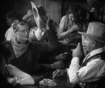 Movie still from “In Old Arizona” (1928), directed by Raoul Walsh – A group of people sitting at a table with hats on; Medium shot, Low angle