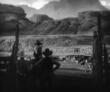 Movie still from “In Old Arizona” (1928), directed by Raoul Walsh – A group of people standing around a herd of sheep; Extreme Wide shot, High angle