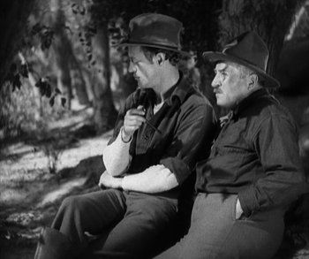 Movie still from “In Old Arizona” (1928), directed by Raoul Walsh – Two men sitting on a bench in the woods; Medium shot, High angle