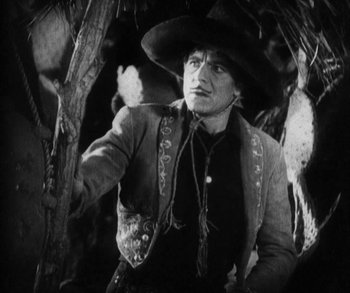Movie still from “In Old Arizona” (1928), directed by Raoul Walsh – A black and white photo of a man wearing a cowboy hat; Medium shot, Low angle