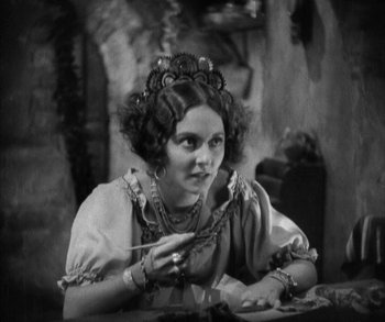 Movie still from “In Old Arizona” (1928), directed by Raoul Walsh – A young woman is sitting at a table with a spoon; Close Up shot, High angle