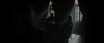 Movie still from “In Secret” (2013), directed by Charlie Stratton – A group of people sitting at a table in a room; Wide shot, Over the shoulder angle