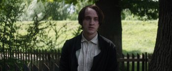 Movie still from “In Secret” (2013), directed by Charlie Stratton – A man in a black jacket standing in front of a tree; Close Up shot, Over the shoulder angle