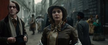 Movie still from “In Secret” (2013), directed by Charlie Stratton – A woman in a hat and a coat on the street; Medium shot, Over the shoulder angle