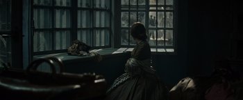 Movie still from “In Secret” (2013), directed by Charlie Stratton – A woman sitting in front of a large window; Wide shot, Over the shoulder angle