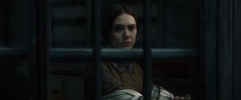 Movie still from “In Secret” (2013), directed by Charlie Stratton – A woman in a brown dress sitting behind bars; Close Up shot, Over the shoulder angle