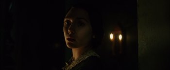 Movie still from “In Secret” (2013), directed by Charlie Stratton – A woman in a dark room with a candle in the background; Close Up shot, Over the shoulder angle
