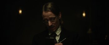 Movie still from “In Secret” (2013), directed by Charlie Stratton – A man in a suit and tie looking at a cell phone; Close Up shot, Low angle