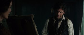 Movie still from “In Secret” (2013), directed by Charlie Stratton – A man in a vest and tie looking at a painting; Medium shot, Over the shoulder angle