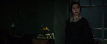 Movie still from “In Secret” (2013), directed by Charlie Stratton – A woman standing in front of a table with fruit on it; Close Up shot, Over the shoulder angle