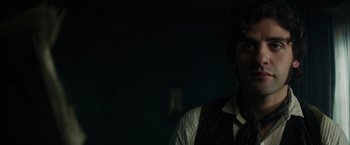 Movie still from “In Secret” (2013), directed by Charlie Stratton – A man wearing a vest and a neck tie in a dark room; Close Up shot, Over the shoulder angle
