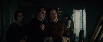 Movie still from “In Secret” (2013), directed by Charlie Stratton – A man and a woman standing next to each other in a dark room; Medium shot, Over the shoulder angle