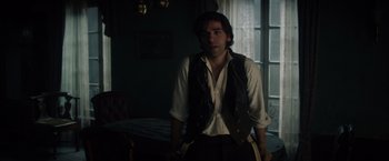 Movie still from “In Secret” (2013), directed by Charlie Stratton – A man standing in front of a window in a room; Medium shot, Over the shoulder angle