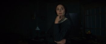 Movie still from “In Secret” (2013), directed by Charlie Stratton – A young woman is standing in a dark room; Close Up shot, Over the shoulder angle