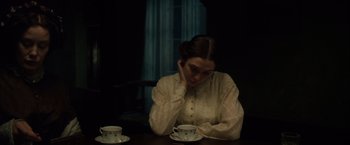 Movie still from “In Secret” (2013), directed by Charlie Stratton – A woman sitting at a table with two cups of coffee; Medium shot, High angle