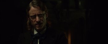 Movie still from “In Secret” (2013), directed by Charlie Stratton – A man with long hair wearing a suit and tie; Close Up shot, Over the shoulder angle