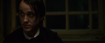 Movie still from “In Secret” (2013), directed by Charlie Stratton – A person wearing a suit and tie; Close Up shot, Over the shoulder angle