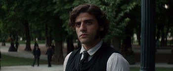 Movie still from “In Secret” (2013), directed by Charlie Stratton – A man in a vest and tie standing in front of trees; Close Up shot, Over the shoulder angle