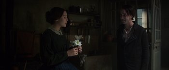 Movie still from “In Secret” (2013), directed by Charlie Stratton – A woman holding a flower in her hands; Medium shot, Over the shoulder angle