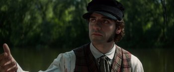 Movie still from “In Secret” (2013), directed by Charlie Stratton – A person wearing a hat and a vest; Close Up shot, Low angle