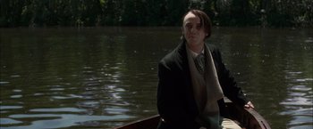 Movie still from “In Secret” (2013), directed by Charlie Stratton – A man in a boat on a body of water; Medium shot, Low angle