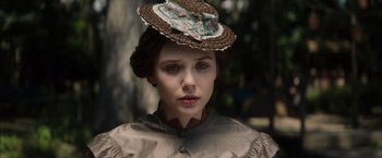 Movie still from “In Secret” (2013), directed by Charlie Stratton – A young woman wearing an old fashioned hat; Close Up shot, Low angle