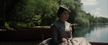 Movie still from “In Secret” (2013), directed by Charlie Stratton – A woman in a dress sitting on top of a wooden bench; Medium shot, Over the shoulder angle