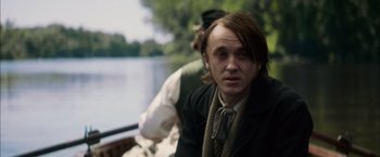 Movie still from “In Secret” (2013), directed by Charlie Stratton – A man with long brown hair wearing a suit and tie; Close Up shot, Over the shoulder angle