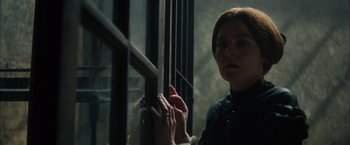 Movie still from “In Secret” (2013), directed by Charlie Stratton – A woman standing next to a window with her hands on the window bars; Close Up shot, Over the shoulder angle