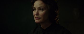 Movie still from “In Secret” (2013), directed by Charlie Stratton – An older woman in a black shirt is looking at the camera; Close Up shot, Over the shoulder angle