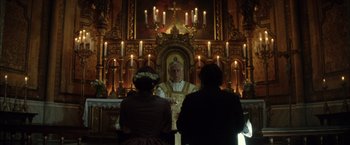 Movie still from “In Secret” (2013), directed by Charlie Stratton – A priest in front of two people in front of a church; Medium shot, Low angle