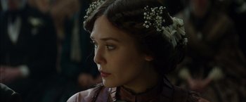 Movie still from “In Secret” (2013), directed by Charlie Stratton – A person wearing a dress with flowers in her hair; Close Up shot, Over the shoulder angle