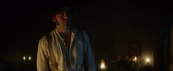 Movie still from “In Secret” (2013), directed by Charlie Stratton – A man in a white shirt is standing in a dark room; Medium shot, Over the shoulder angle