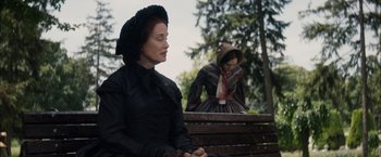 Movie still from “In Secret” (2013), directed by Charlie Stratton – A woman sitting on a bench next to another woman; Medium shot, Over the shoulder angle