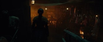 Movie still from “In Secret” (2013), directed by Charlie Stratton – A woman standing in front of an audience in a dimly - lit room; Wide shot, Over the shoulder angle