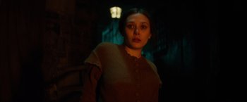 Movie still from “In Secret” (2013), directed by Charlie Stratton – A woman in a brown sweater standing next to a street light; Medium shot, Low angle