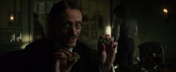 Movie still from “In Secret” (2013), directed by Charlie Stratton – A man holding two dominoes in his hands; Close Up shot, Over the shoulder angle